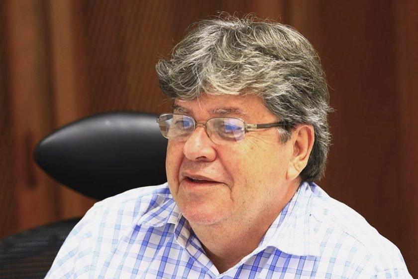 João Azevêdo, candidato a reeleição para o governo da Paraíba pelo Cidadania. Ele é branco, tem cabelo ondulado, grisalho e olha para frente, sentado diante de uma tela - Metrópoles
